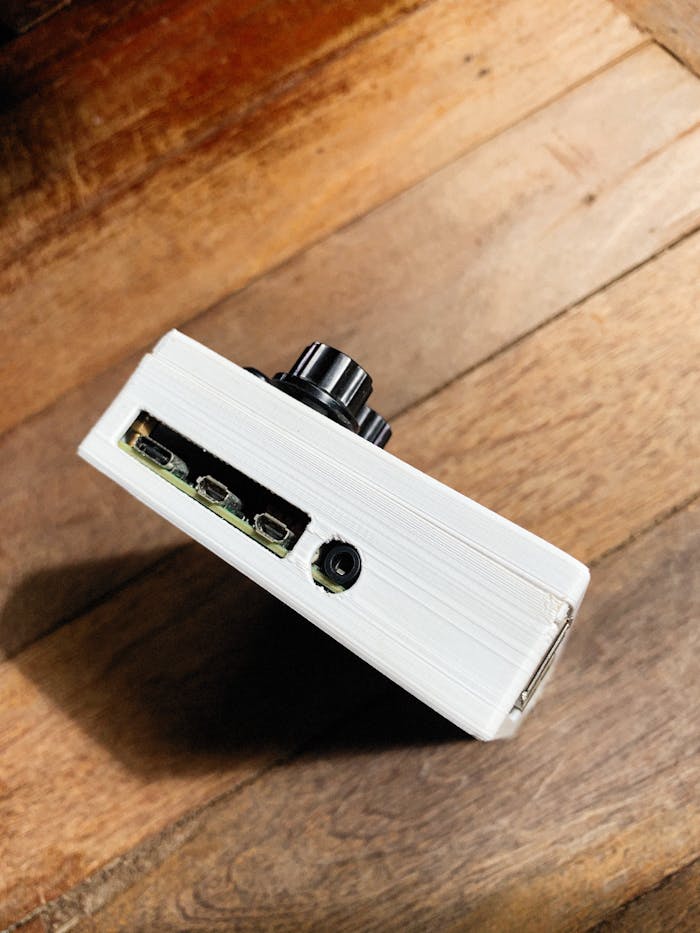 Close-up of a white electronic device on wooden surface shot at high angle.